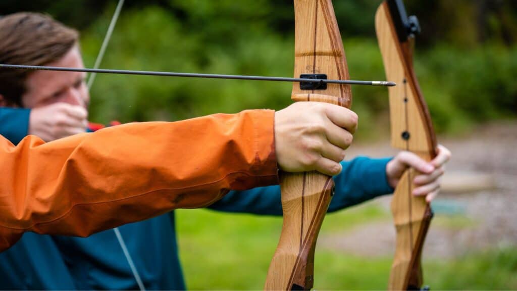 Mann som skyter bueskytter i skogen.
