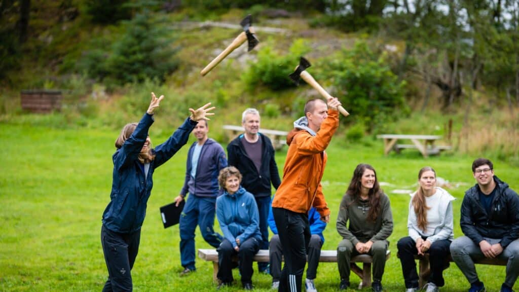 Unger som deltar i utendørs aktiviteter med økser i Sotra Villmarkssenter, naturskjønn omgivelse for eventyr og teambuilding.