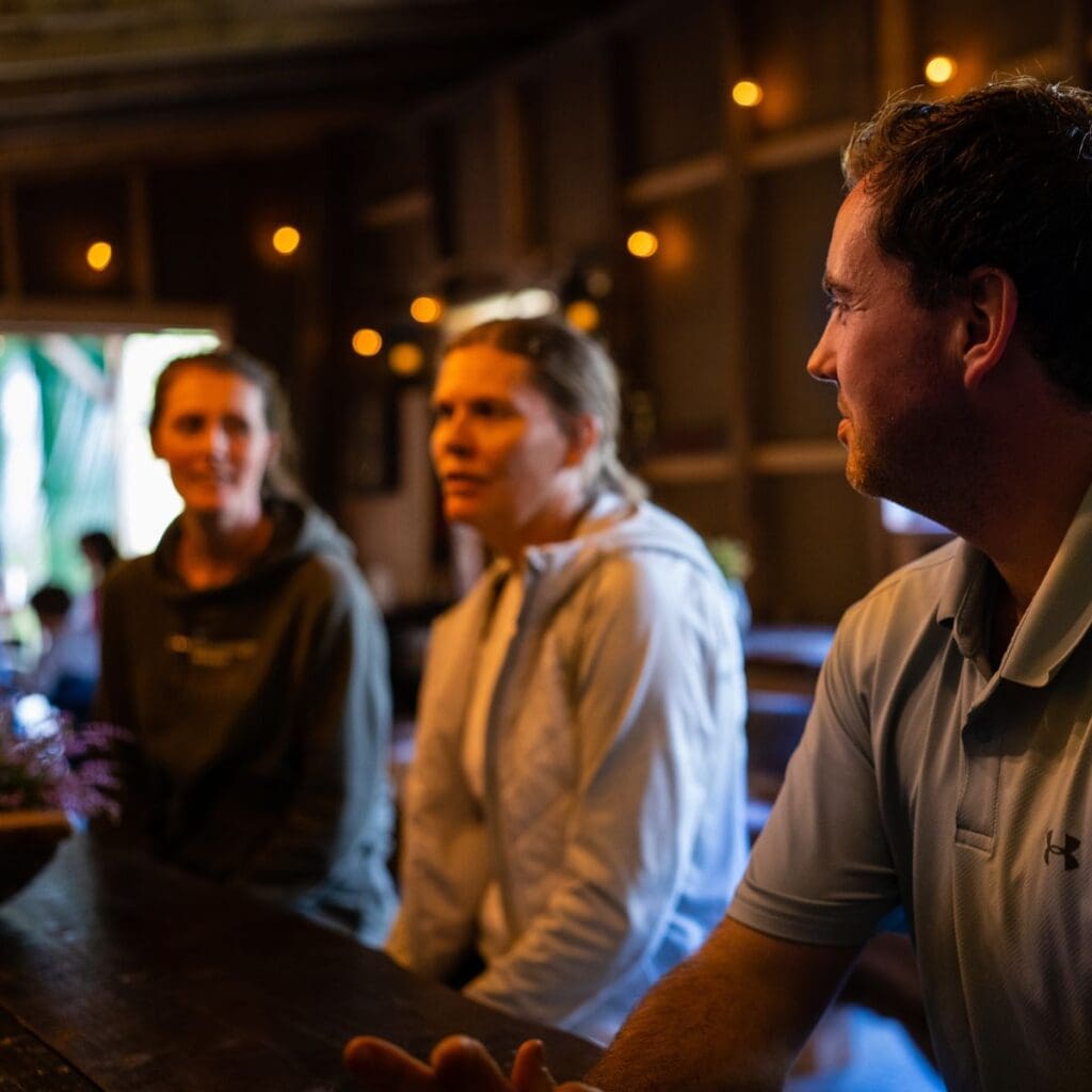 Detaljert bilde av mennesker i samtale, innendørs, med varm belysning.