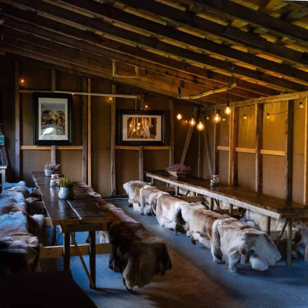 Hytteinteriør med reinsdyrskinn, koselig belysning og villmarksatmosfære på Sotra Villmarkssenter i Norge.