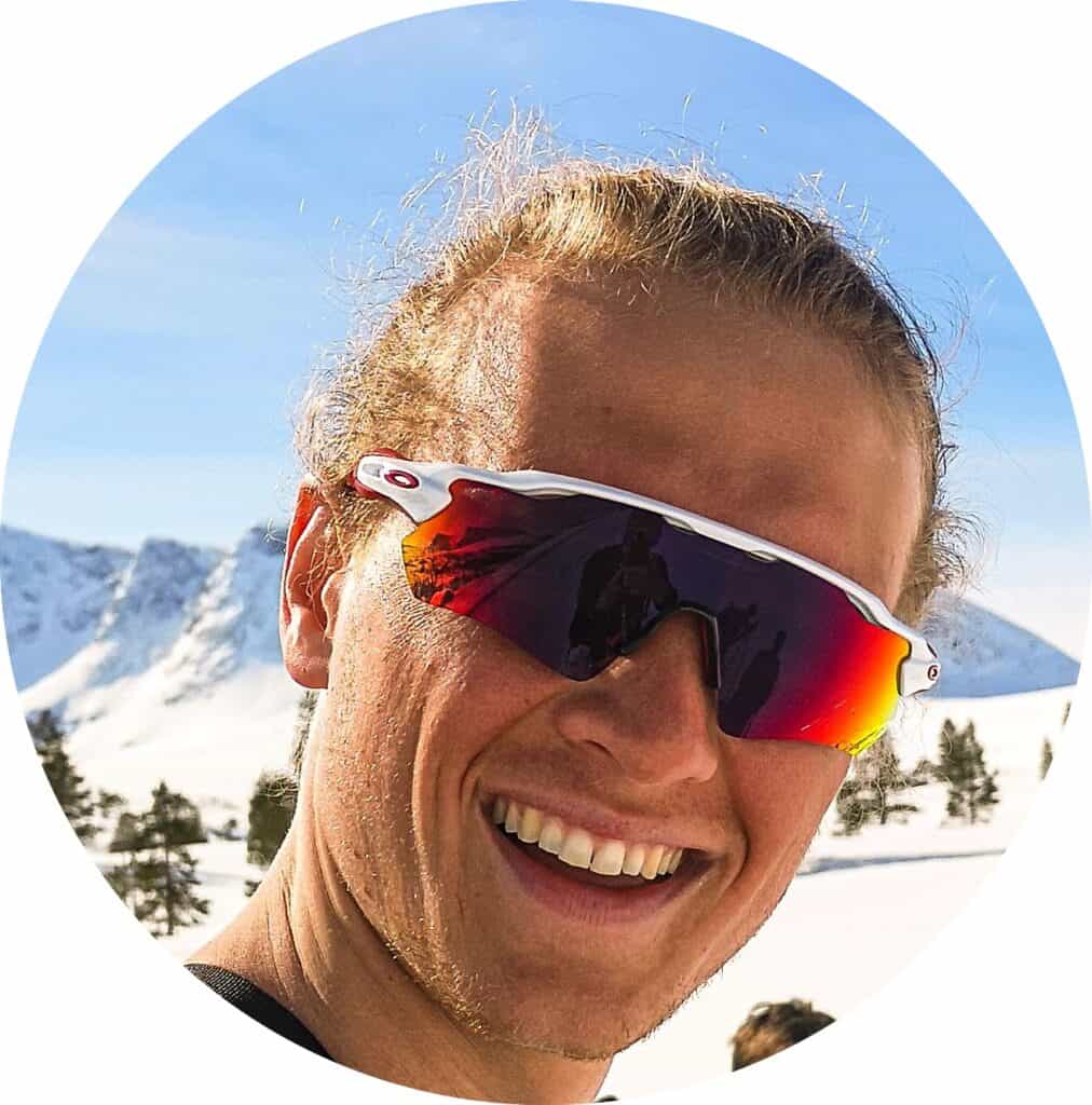 Ekstremt sportslig idrettsutøver med ski og solbriller i snødekt landskap.